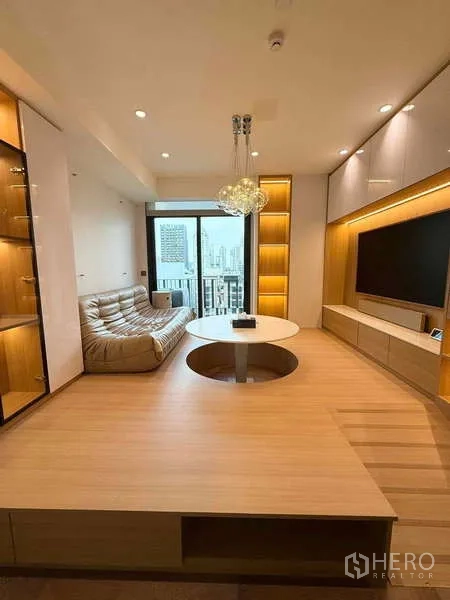 Condominium for rent in Watthana, Bangkok - Elevated platform living room with sofa, TV console, and sliding doors opening to the balcony.