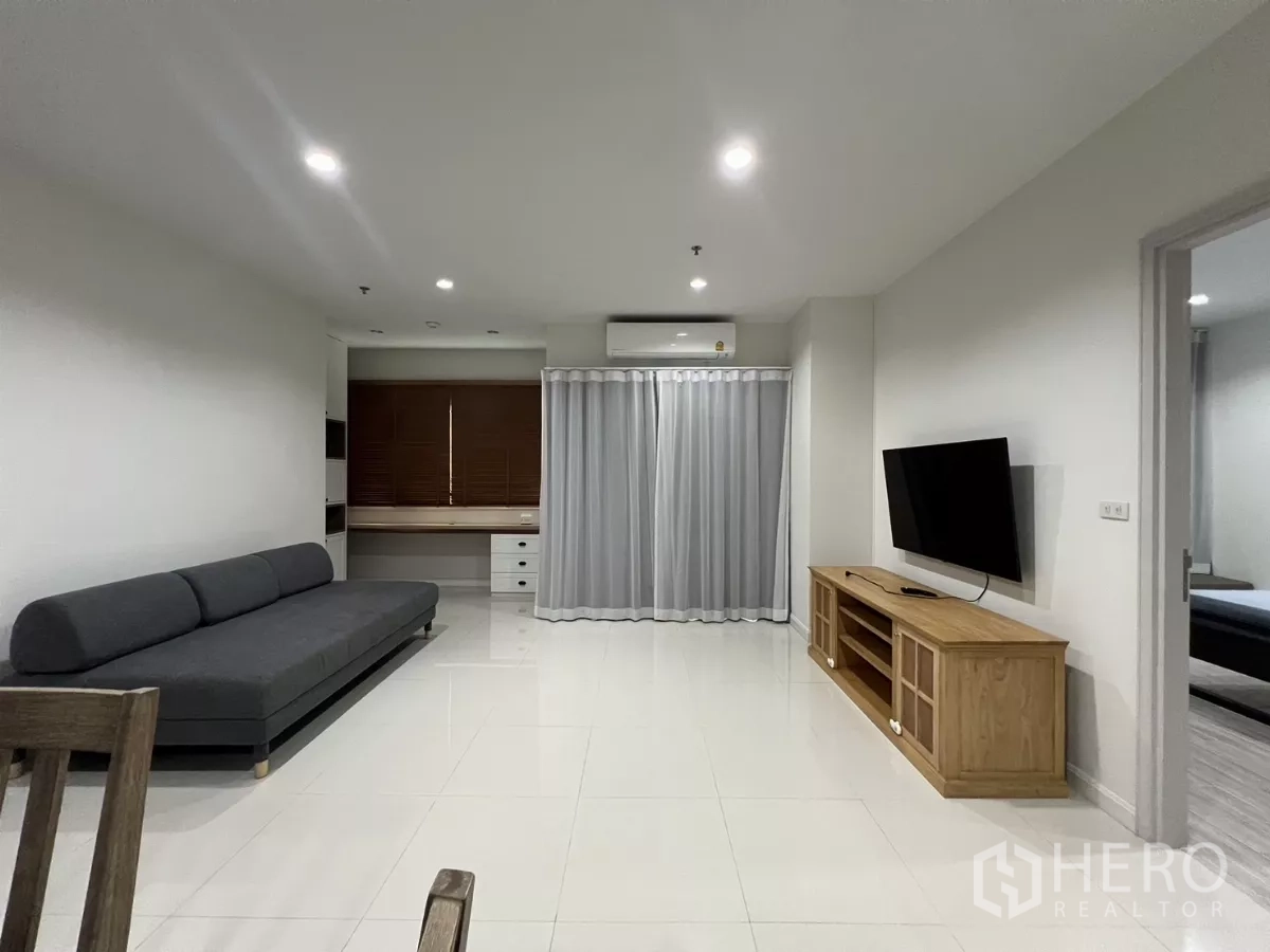 คอนโด ให้เช่าในBang Kapi, Bangkok - ห้องนั่งเล่นสว่าง โซฟาสีเทา ทีวีติดผนัง พร้อมโต๊ะทำงานบิวท์อิน