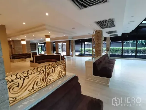 零售空间 出租在Pathum Wan, Bangkok - 带金色花纹隔断的休息区，大面积窗墙与浅色地面。