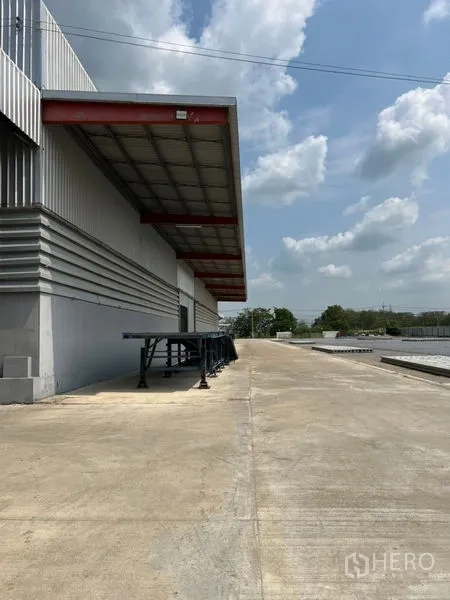 Warehouse for rent in Pathum Thani - Covered loading bay with a raised dock and long concrete apron along the warehouse.