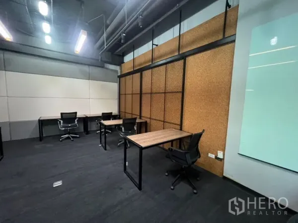 办公空间 出租 - 开放办公区，软木质感造型墙，多张书桌与线性顶灯。