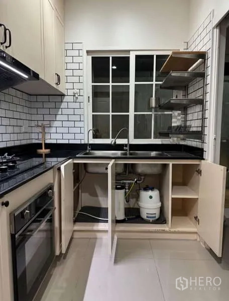 Detached House for rent in Bueng Kum, Bangkok - Fitted kitchen with gas hob, oven, black countertops and white subway tiles.