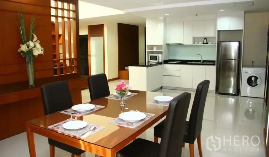 Apartment for rent in Khlong Toei, Bangkok - Dining table for four beside a white modern kitchen with fridge and washing machine