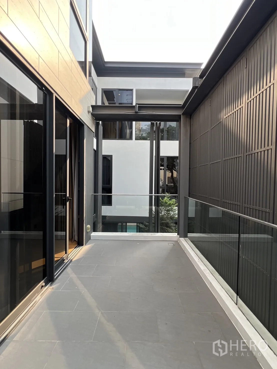 独立式住宅 出租在Suan Luang, Bangkok - 侧向露台通道，玻璃栏杆夹于建筑之间