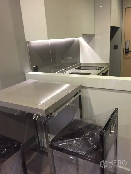 公寓 出租在Watthana, Bangkok - 紧凑厨房，电磁炉与橱柜灯，吧台和高脚凳。