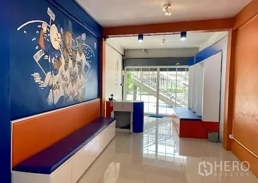 อาคารพาณิชย์ ให้เช่าในKhlong Toei, Bangkok - พื้นที่ชั้นล่างสว่าง โปร่ง กระจกหน้าร้าน พื้นกระเบื้องเงา และม้านั่งยาว พร้อมภาพวาดธีมกีฬา