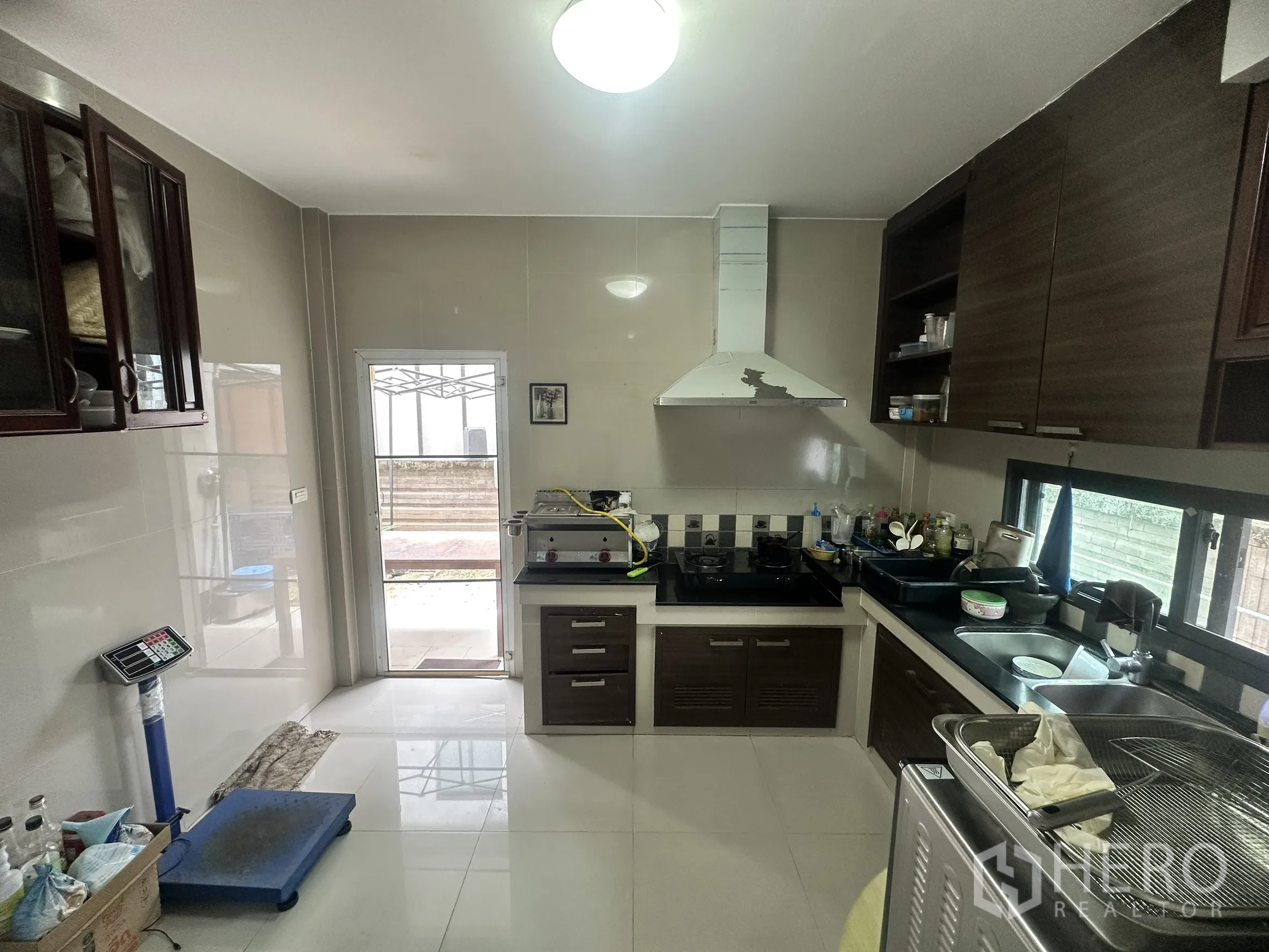Detached House for sale in Pak Kret, Nonthaburi - Enclosed kitchen with cooktop, range hood, cabinets, and side door.