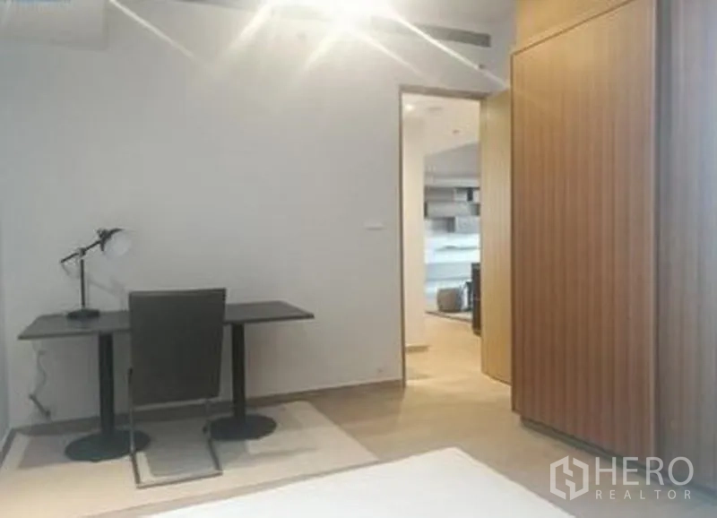 Condominium for sale in Sathon, Bangkok - Bedroom corner with study desk, lamp and wood‑grain wardrobe.