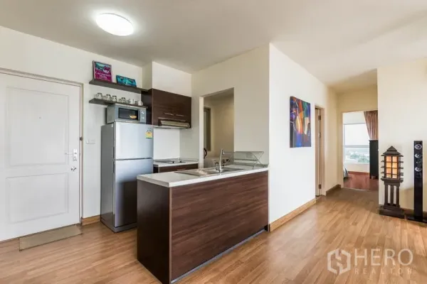 คอนโด ให้เช่าในBang Na, Bangkok - ทางเข้าและครัวแบบเปิด ตู้ลายไม้ เคาน์เตอร์บาร์ และโถงทางเดินสู่ห้องนอน