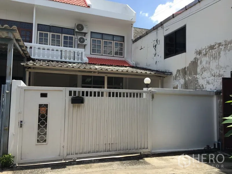 ทาวน์เฮาส์ ให้เช่าในPhra Khanong, Bangkok - ด้านหน้าทาวน์เฮ้าส์สองชั้น ประตูรั้วสีขาว มีระเบียงและหลังคากระเบื้องสีแดง