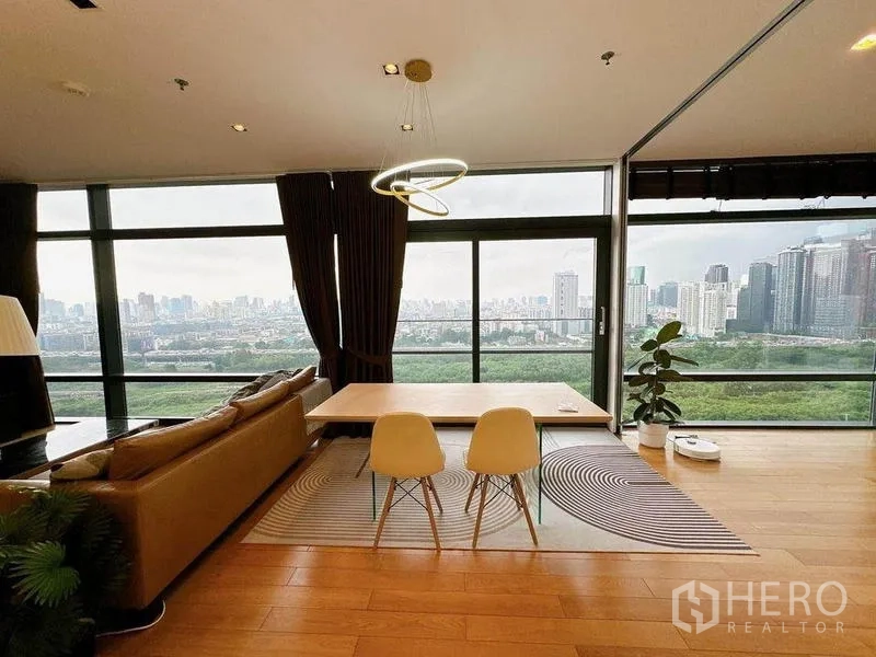 Condominium for rent in Ratchathewi, Bangkok - Open-plan living and dining area with large panoramic windows, ring pendant light, and sweeping skyline and park views.