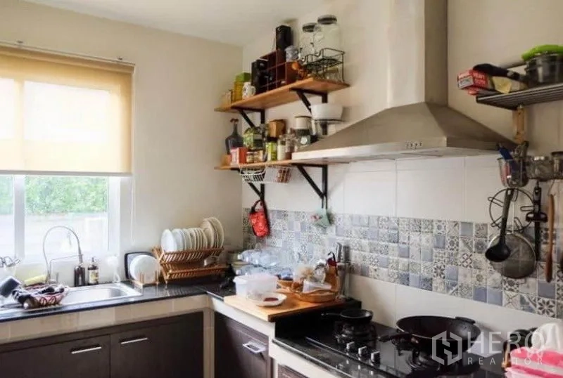 Detached House for rent or sale in Khlong Sam Wa, Bangkok - Functional kitchen with L-shaped counters, window, range hood and patterned tile backsplash.
