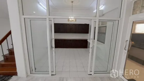 Townhouse for rent in Watthana, Bangkok - Enclosed dining room behind glass doors with dark wood built-in cabinets and chandelier.