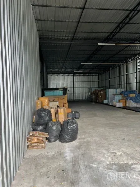 คลังสินค้า ให้เช่าในLat Phrao, Bangkok - ภายในโกดังเพดานสูง ผนังเมทัลชีท พื้นคอนกรีต ไฟฟลูออเรสเซนต์และกล่องสินค้าวางเรียงริมผนัง