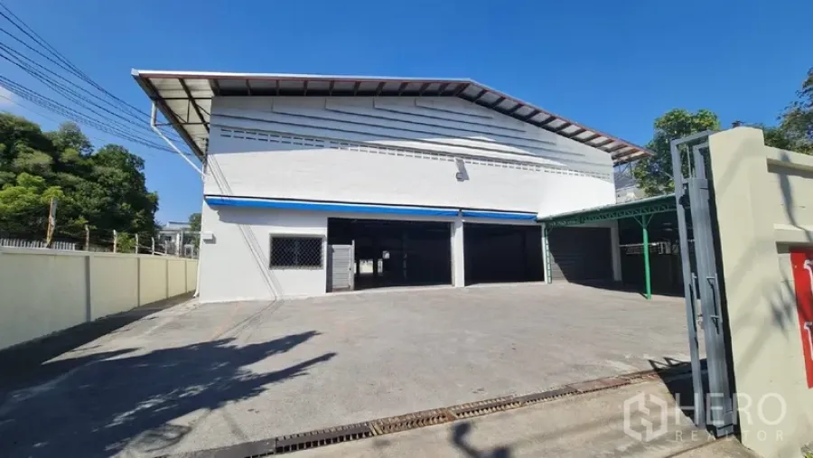 Warehouse for rent in Khlong Toei, Bangkok - Front exterior of a white warehouse with wide concrete yard and gated entrance.