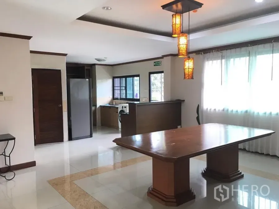 อพาร์ทเมนท์ ให้เช่าในWatthana, Bangkok - พื้นที่รับประทานอาหารแบบเปิดพร้อมโต๊ะไม้ โคมไฟแขวน และครัวกึ่งเปิดข้างหน้าต่างบานใหญ่