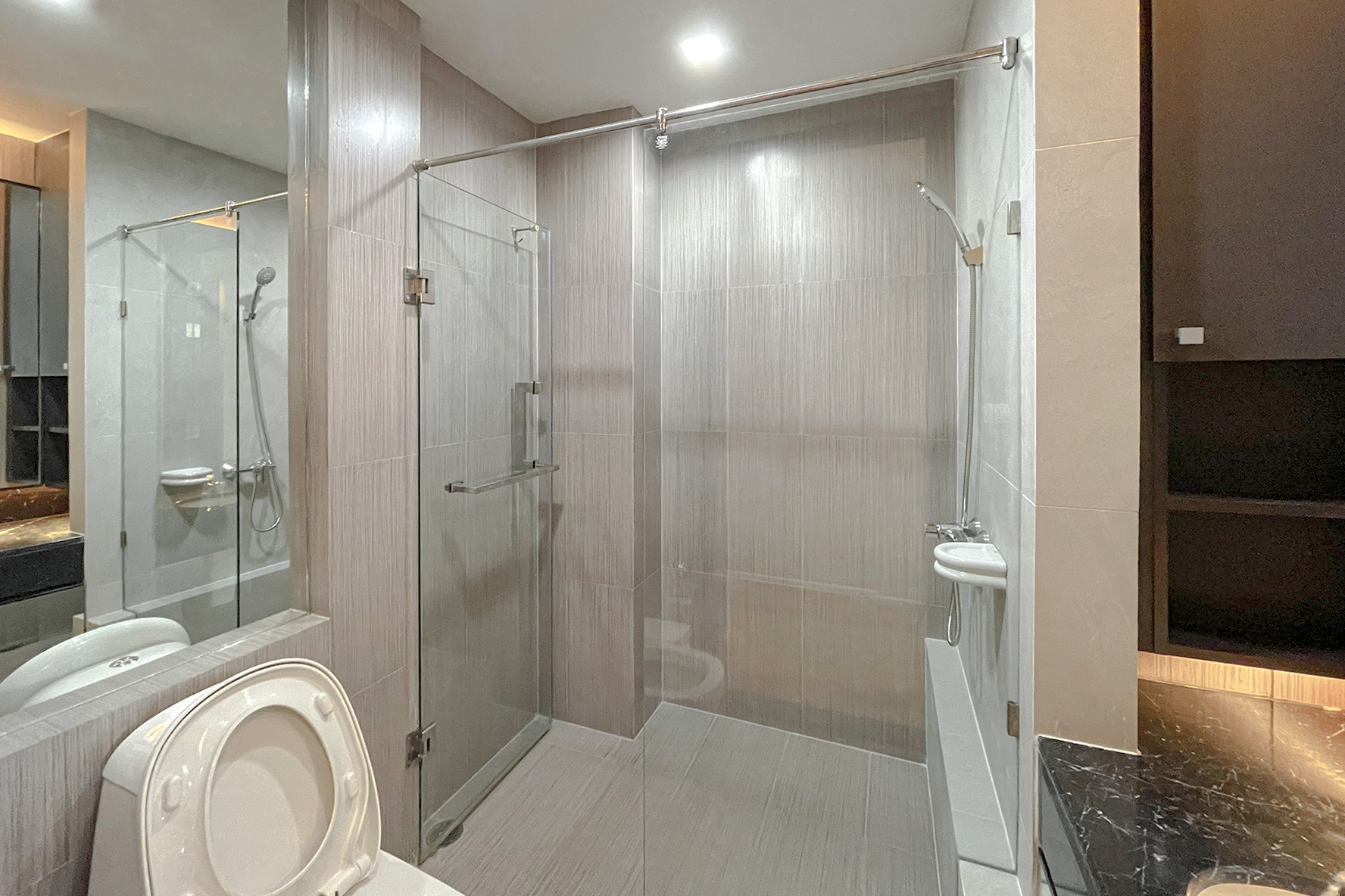 公寓 出租在Watthana, Bangkok - 现代卫浴，玻璃淋浴间与马桶，灰色中性瓷砖。