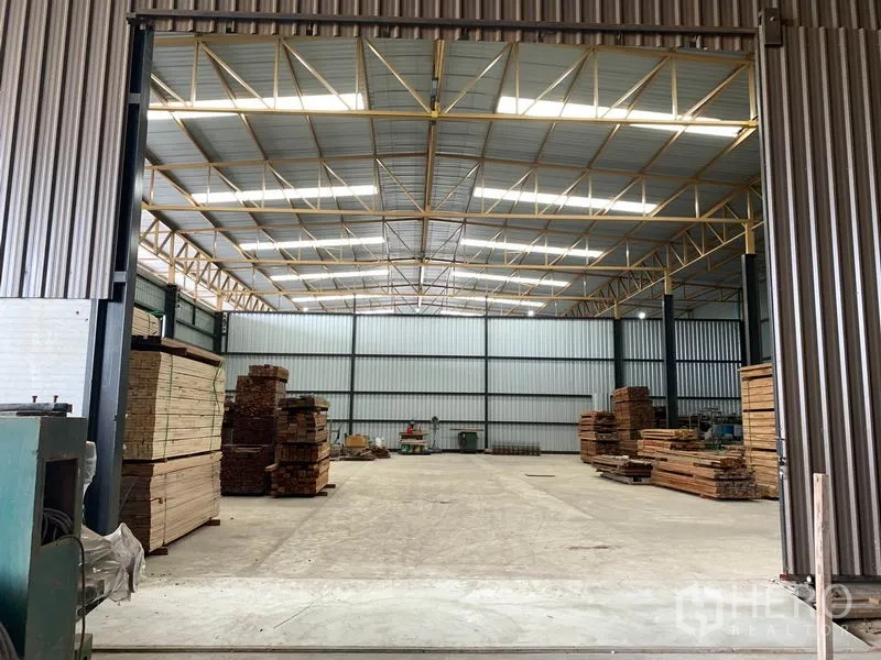 Home Office for rent in Lam Luk Ka, Pathum Thani - Large storage hall with steel cladding and stacks of timber.