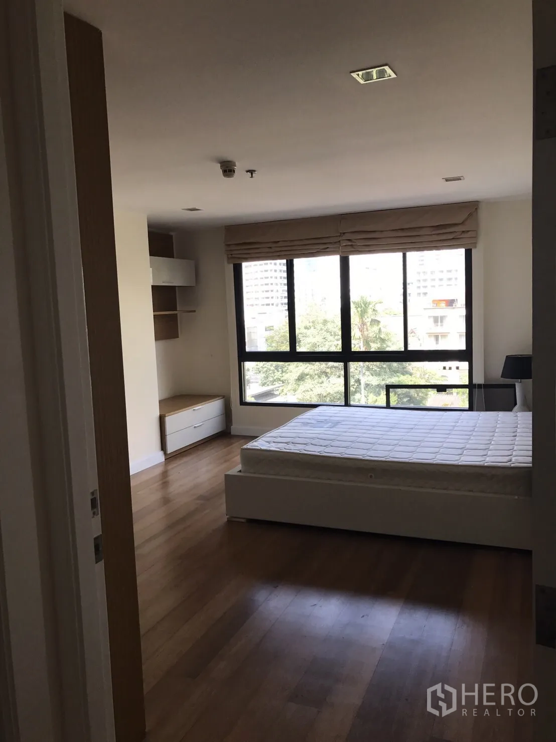 คอนโด ให้เช่าหรือขายในWatthana, Bangkok - ห้องนอนรับแสงธรรมชาติ หน้าต่างบานกว้าง เห็นวิวต้นไม้ และเตียงบนพื้นไม้.