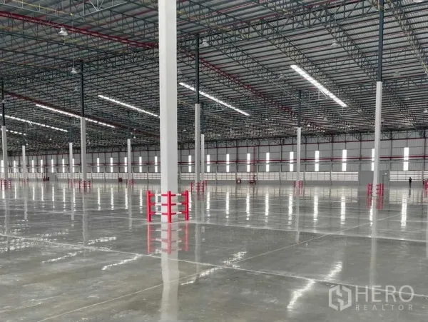 工厂 出租在Si Racha, Chon Buri - 柱列特写，红色防撞护栏、条形采光窗与高天棚灯。