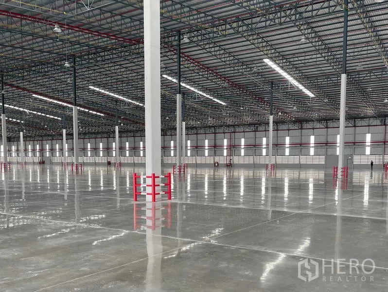 工厂 出租在Si Racha, Chon Buri - 柱列特写，红色防撞护栏、条形采光窗与高天棚灯。