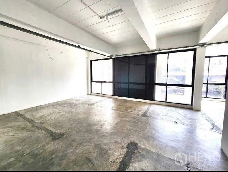 Office Space for rent or sale in Din Daeng, Bangkok - Sunlit office room with wide black-framed windows and exposed ceiling track.