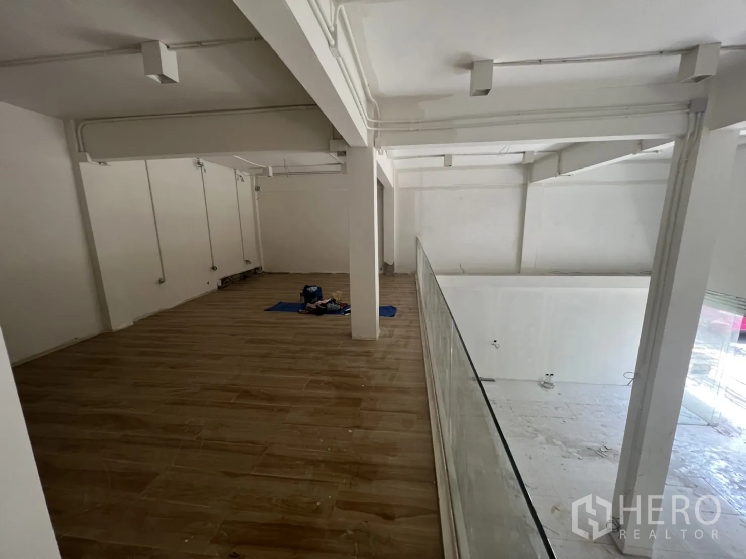 店屋 出租在Watthana, Bangkok - 夹层木地板与玻璃栏杆，可俯瞰下方展示区。