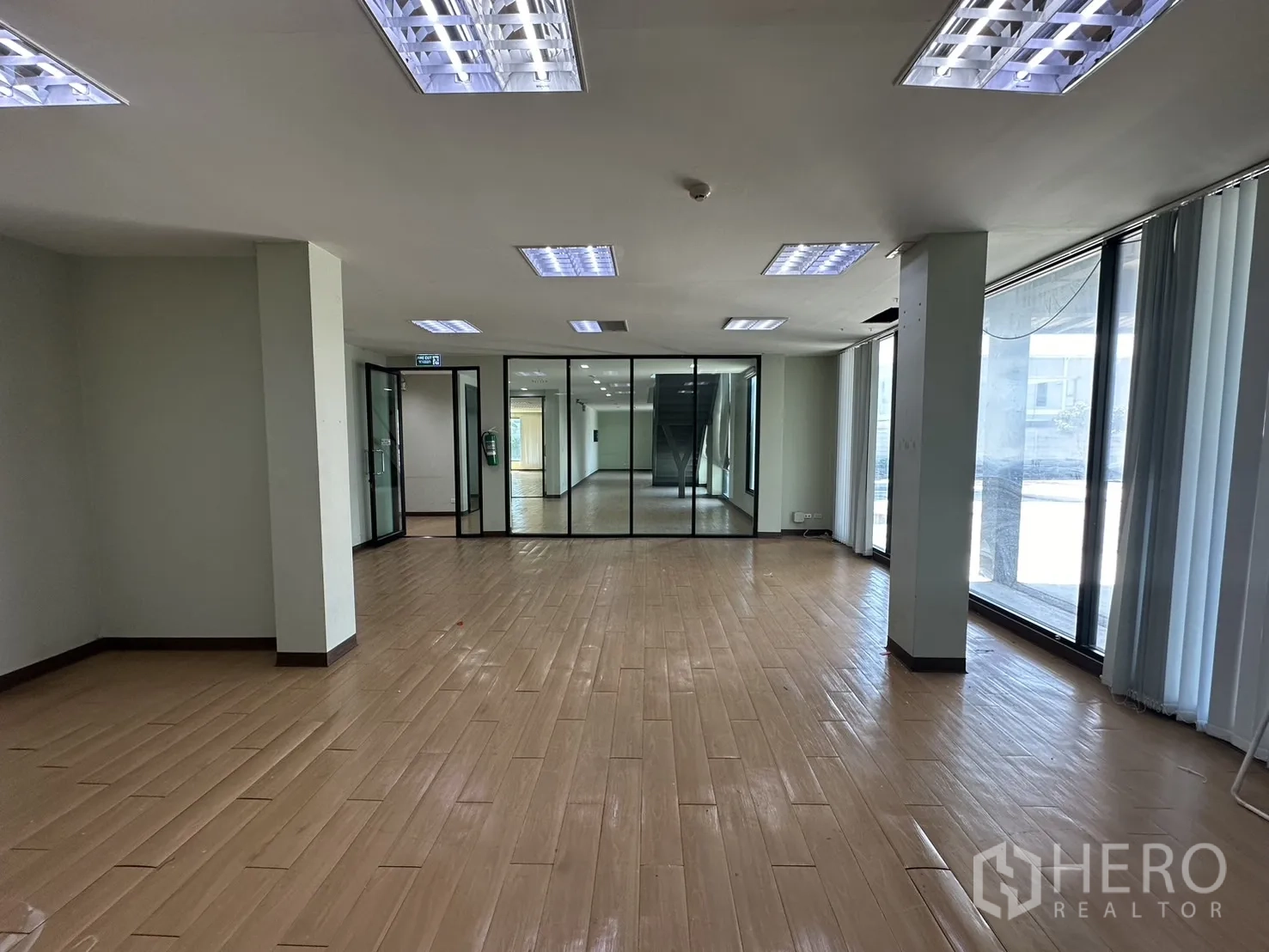 Home Office for rent in Prawet, Bangkok - Open office with glass partitions and floor-to-ceiling windows facing the car park.