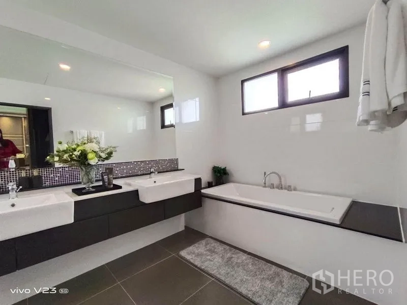 Detached House for sale in Wang Thonglang, Bangkok - Spacious bathroom featuring double vanity, large mirror, built-in bathtub and upper windows.