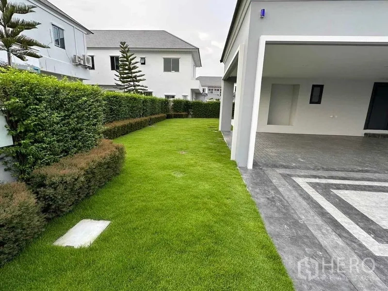 บ้าน ขายในLat Krabang, Bangkok - ลานสวนข้างบ้านติดโรงจอดรถแบบมีหลังคาและทางรถเข้าปูพื้นกระเบื้อง ล้อมด้วยแนวพุ่มไม้