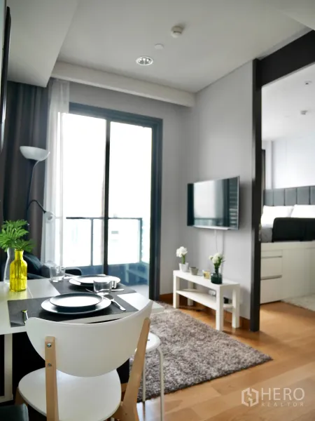 Condominium for rent in Khlong Toei, Bangkok - Compact dining nook for two beside the balcony, looking toward the TV console and bedroom entrance.