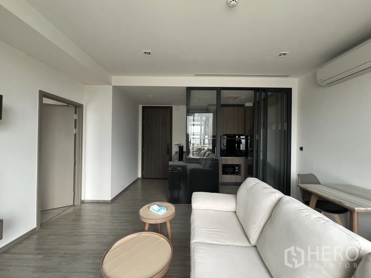 คอนโด for rent in Watthana, Bangkok - ห้องนั่งเล่นพร้อมโซฟารูปตัวแอลสีครีม โต๊ะกาแฟคู่ และครัวกั้นกระจก
