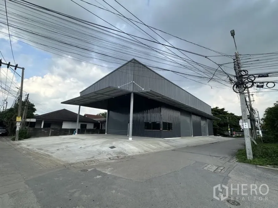 คลังสินค้า ให้เช่าในBang Kapi, Bangkok - มุมมองริมถนนของโกดังสีเข้ม พร้อมท่าโหลดมีหลังคาและที่จอดรถกลางแจ้ง