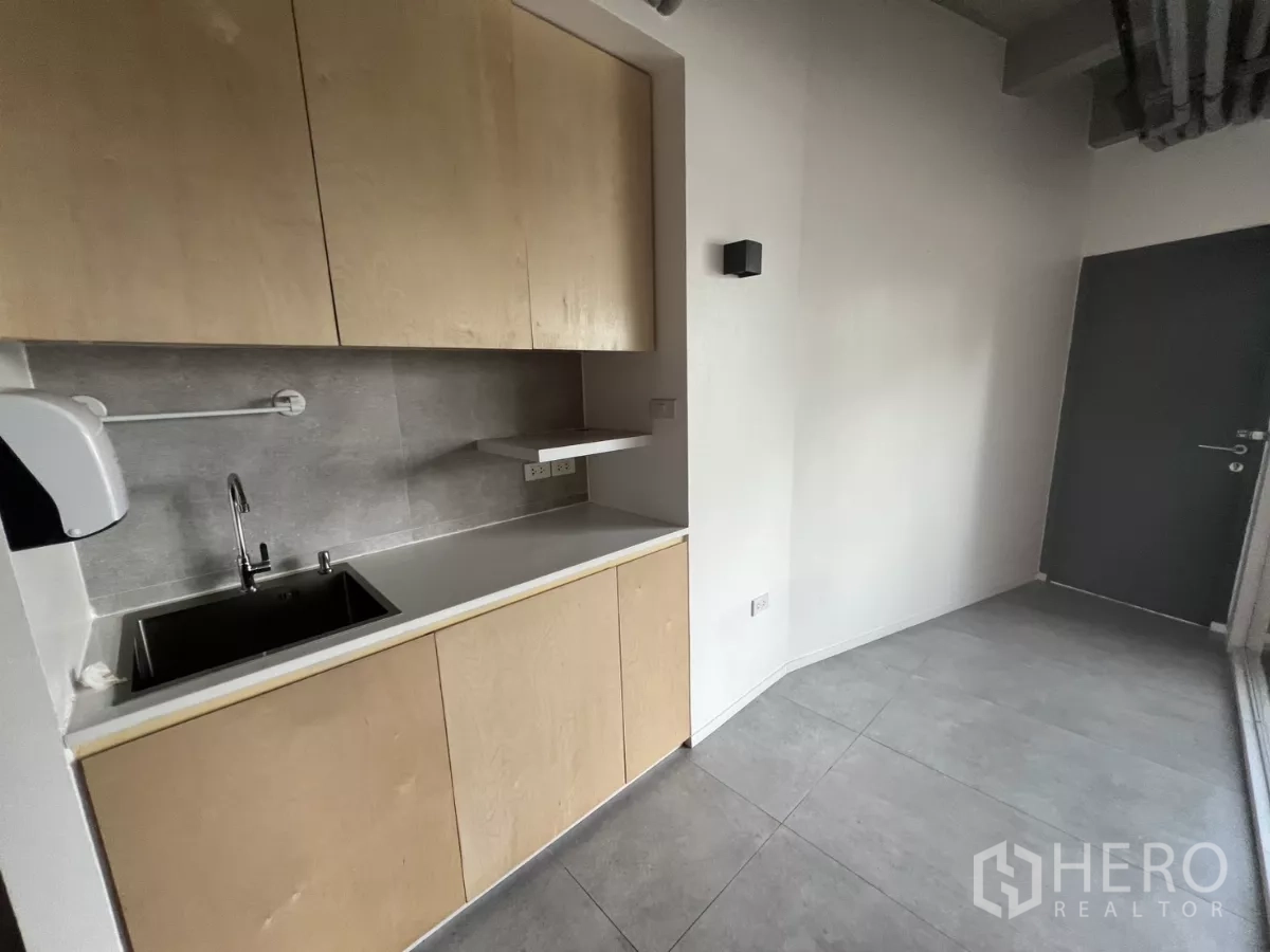 零售空间 出租在Khlong Toei, Bangkok - 紧凑茶水间，配水槽与吊柜和灰色瓷砖墙面。