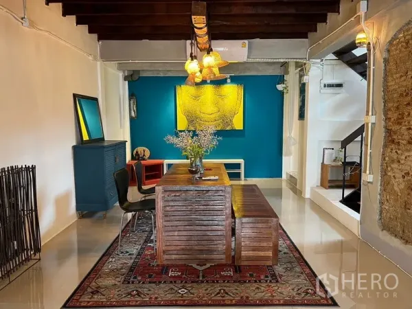 Townhouse for rent in Ratchathewi, Bangkok - Dining area featuring a teal accent wall, warm hanging lamps and a wooden table on a rug.