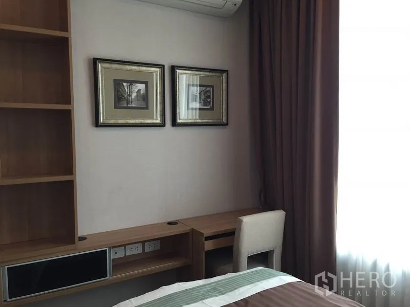 Condominium for rent in Ratchathewi, Bangkok - Bedroom corner featuring a built-in desk, shelving and framed pictures next to a window.