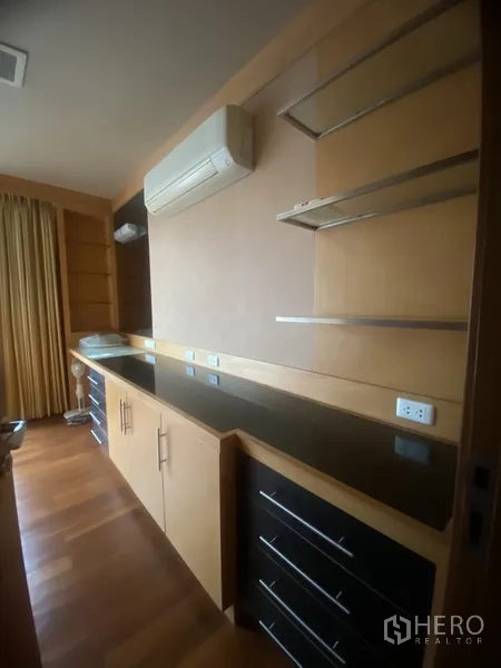 Condominium for rent in Pathum Wan, Bangkok - Work or storage nook with long countertop, shelves, drawers and wall-mounted air-conditioning.