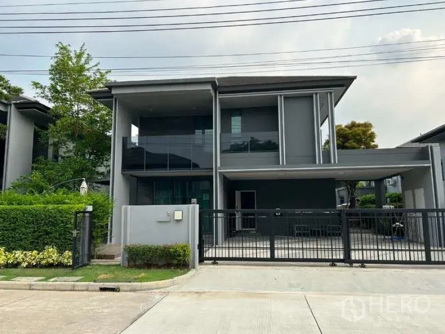 Detached House for rent in Bang Kapi, Bangkok - Modern two-storey grey detached house with gated driveway and covered carport.