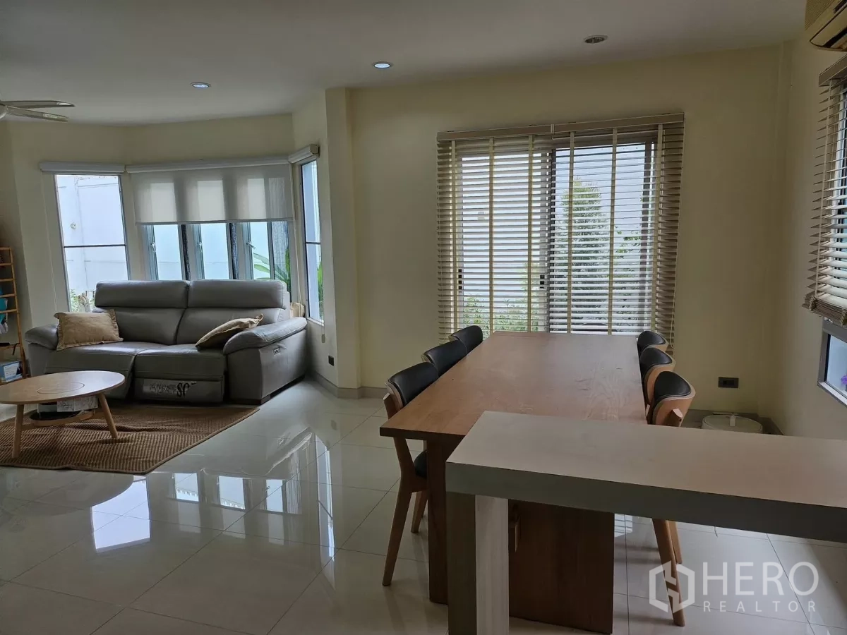 独立式住宅 出租在Khlong Toei, Bangkok - 开放式客厅，落地窗采光充足，灰色沙发与茶几面向绿意。