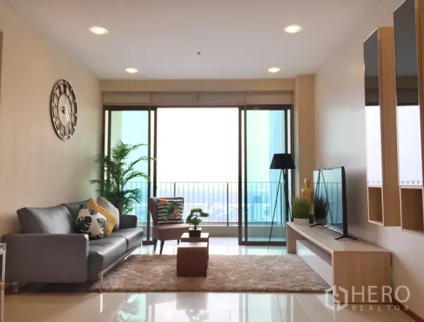 คอนโด ให้เช่าหรือขายในKhlong Toei, Bangkok - ห้องนั่งเล่นสว่าง โซฟาเทา พรม และระเบียงวิวเมือง