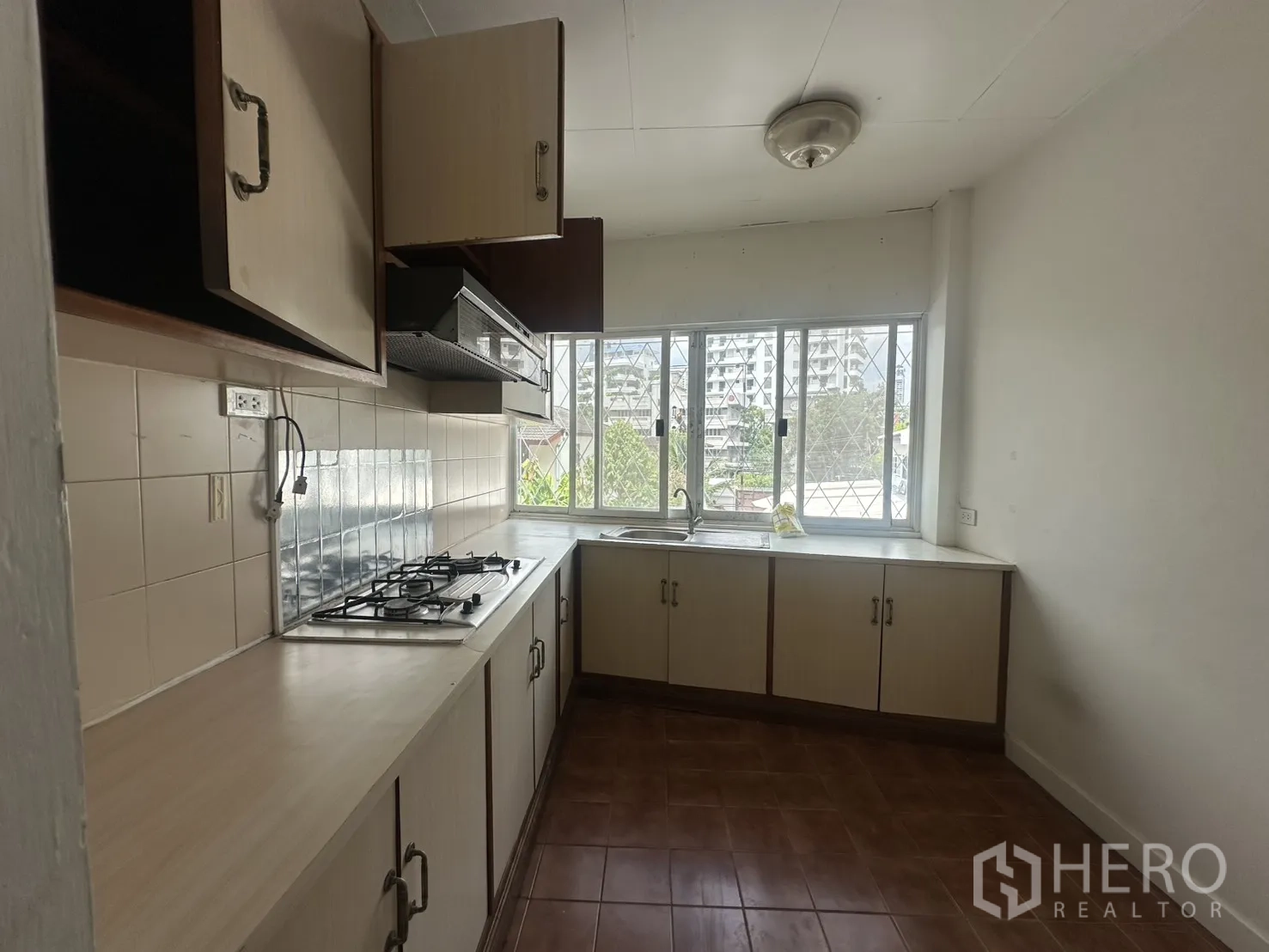 Home Office for rent in Watthana, Bangkok - Linear kitchen with gas cooktop, cabinets, and large windows.