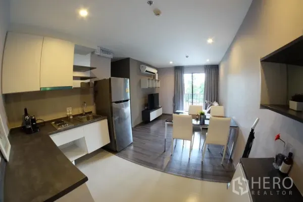 คอนโด ให้เช่าในWatthana, Bangkok - ห้องครัวแบบเปิดเชื่อมพื้นที่นั่งเล่น มีตู้เย็นสแตนเลส โต๊ะทานอาหาร ชั้นวางทีวี และประตูออกระเบียง ใกล้ BTS อ่อนนุช