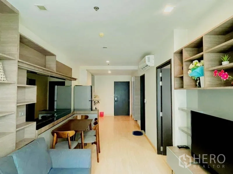 Condominium for rent - Open-plan living, dining, and kitchen with shelving and a dining table.