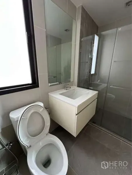 联排别墅 出租在Lat Phrao, Bangkok - 采光良好的浴室，设洗手台、坐便器与玻璃淋浴间，旁有窗户。