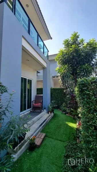 Detached House for rent or sale in Saphan Sung, Bangkok - Rear-side lawn with sliding doors and a covered terrace beneath the upper balcony.