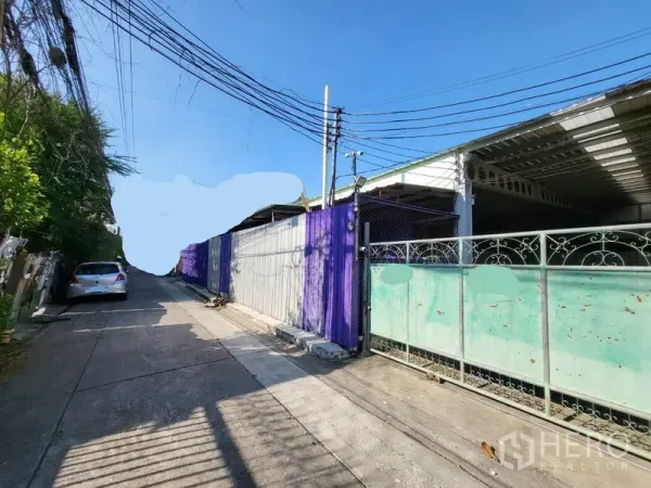 Warehouse for rent in Din Daeng, Bangkok - Gated entrance of a Din Daeng, Bangkok warehouse on a quiet lane with metal fence and overhead cables.