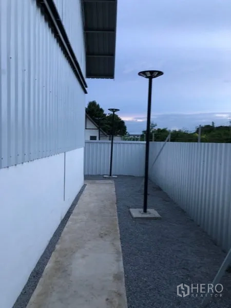 คลังสินค้า ให้เช่าในBueng Kum, Bangkok - ทางเดินโรยกรวดข้างอาคาร รั้วรอบและเสาไฟส่องสว่าง