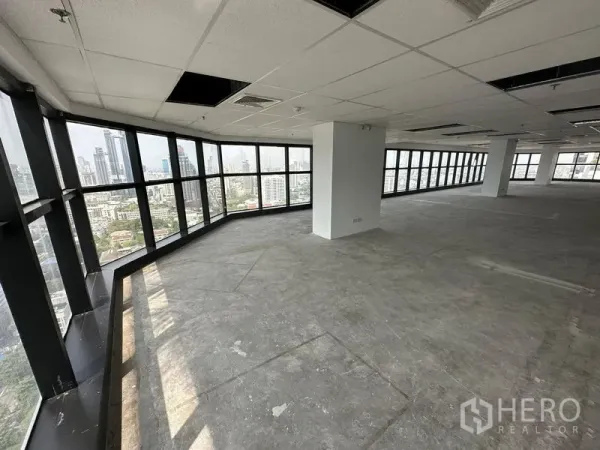 办公空间 出租 - 转角工作区，环绕落地窗与裸露混凝土地面，采光充足。