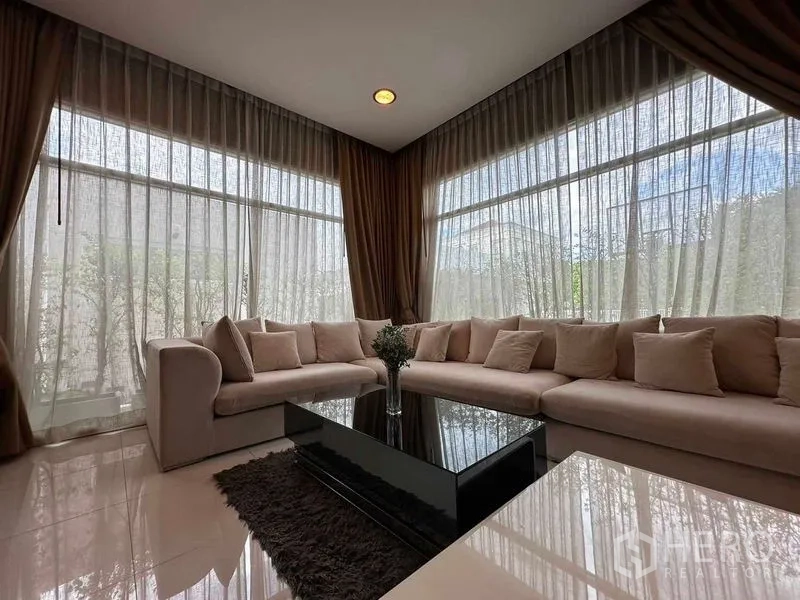 Detached House for rent or sale in Bang Phli, Samut Prakan - Cozy lounge with L‑shaped sofa, sheer curtains and garden view