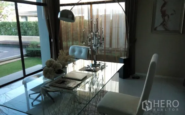 Detached House for rent or sale in Prawet, Bangkok - Glass-top study desk with curved lamp and garden view through large windows.